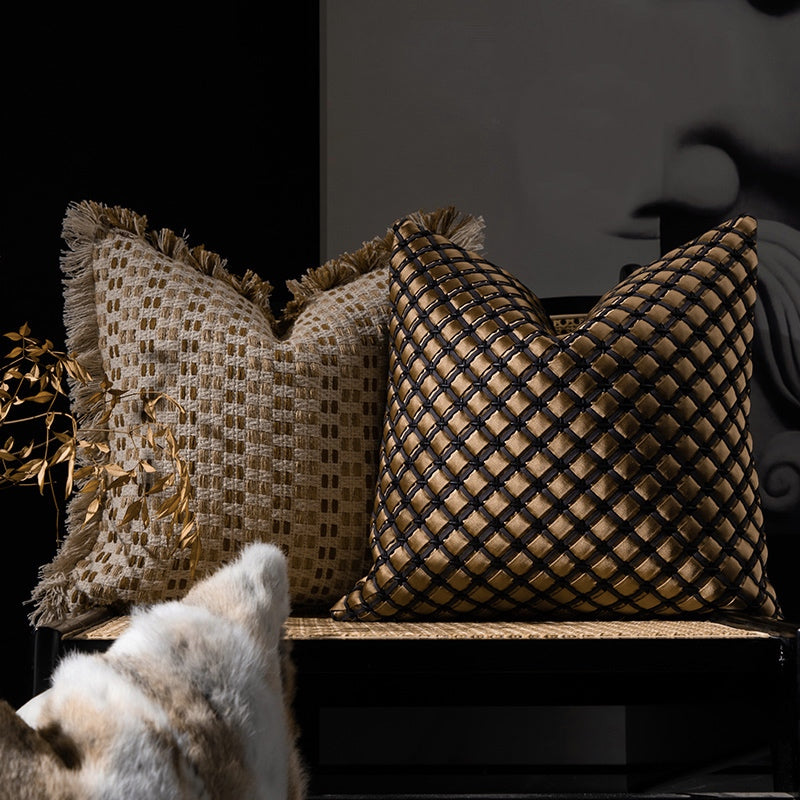 Woven decorative cushion covers in beige and bronze tones styled on a modern chair with textured fringe detailing