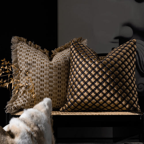 Woven decorative cushion covers in beige and bronze tones styled on a modern chair with textured fringe detailing